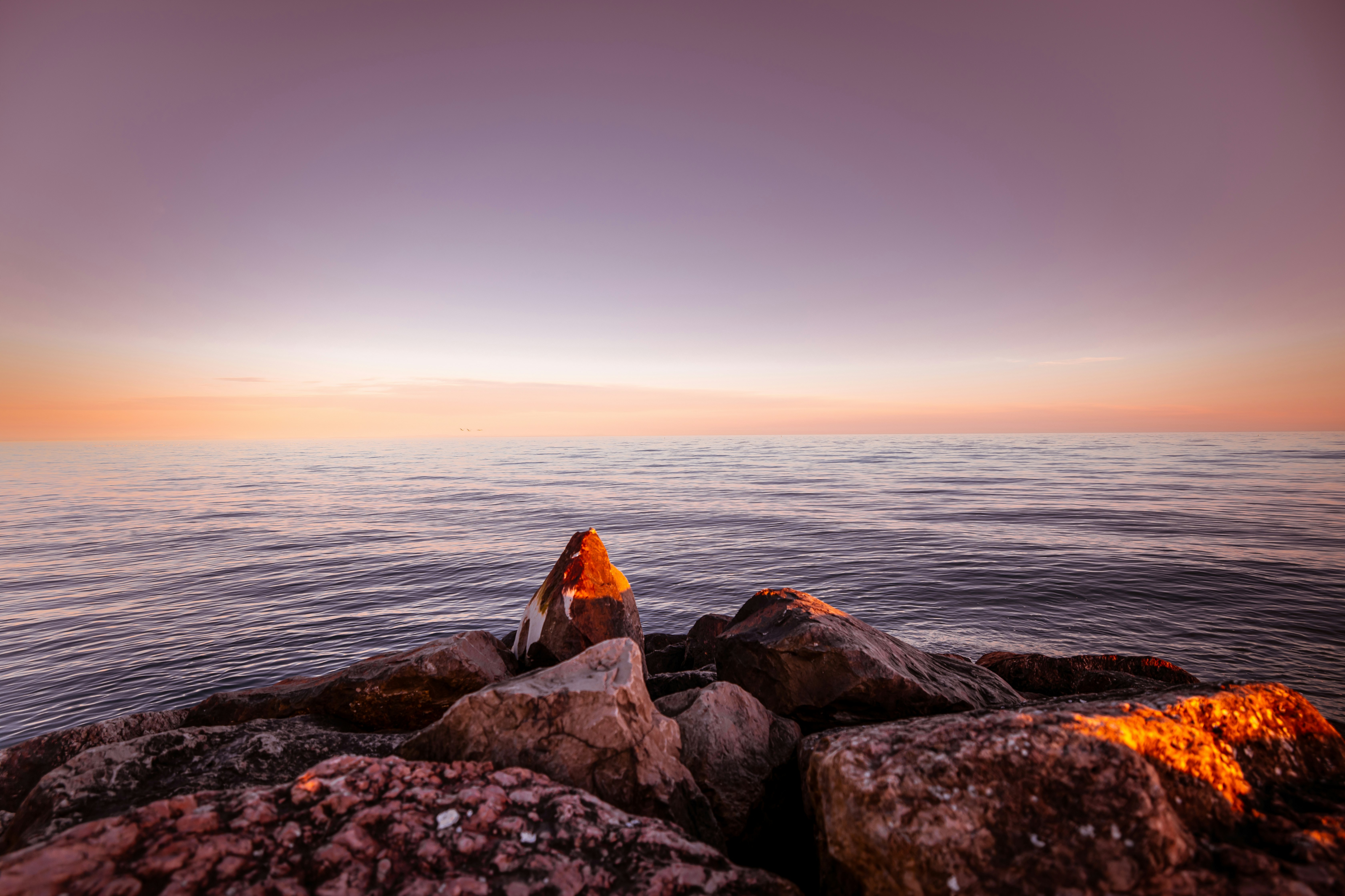 brown and gray rocks near body of water during sunset